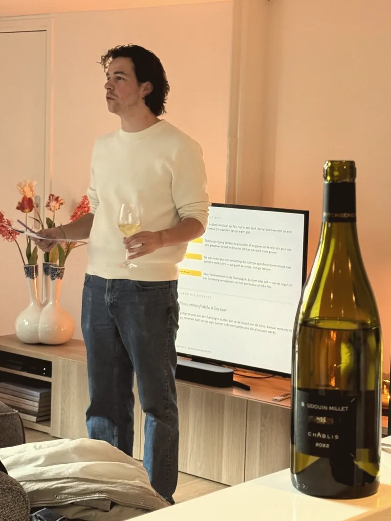Max met een glas witte wijn naast de fles en een scherm met de proefvolgorde